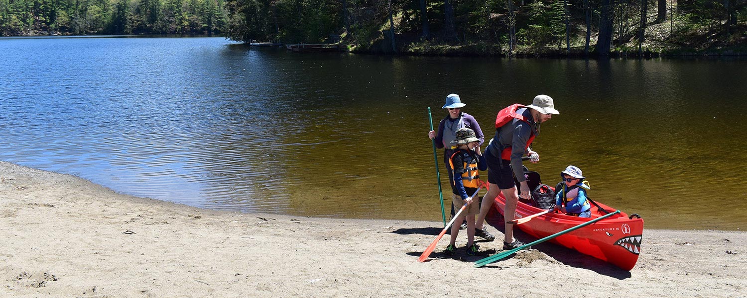 family preparing for a canoe trip on lake luzerne in summer