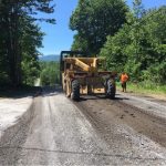 An image of a tractor on a rustic, rural road doing work